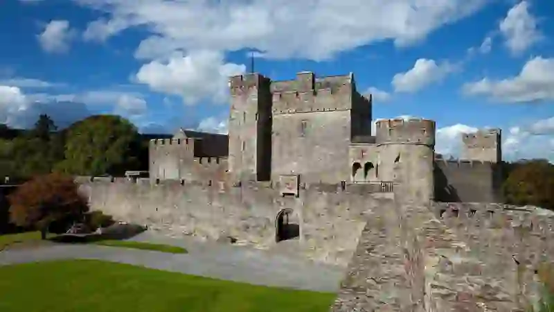 View across the walls and towers of Cahir Castle, County Tipperary, beneath a blue sky with scattered clouds.