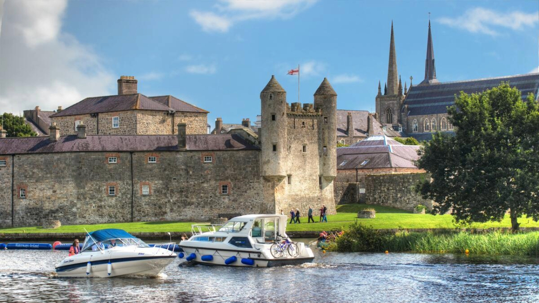 Boats cruise the River Erne past Enniskillen Castle in County Fermanagh, with St Macartin's Cathedral behind.