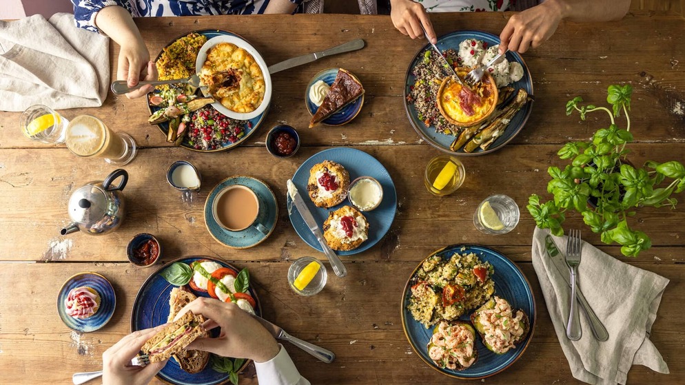 People enjoying brunch and coffee around a table filled with colourful dishes and desserts in Mount Congreve Gardens, County Waterford.