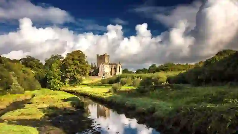 Tintern Abbey reflected in a tranquil stream amid the countryside of County Wexford.