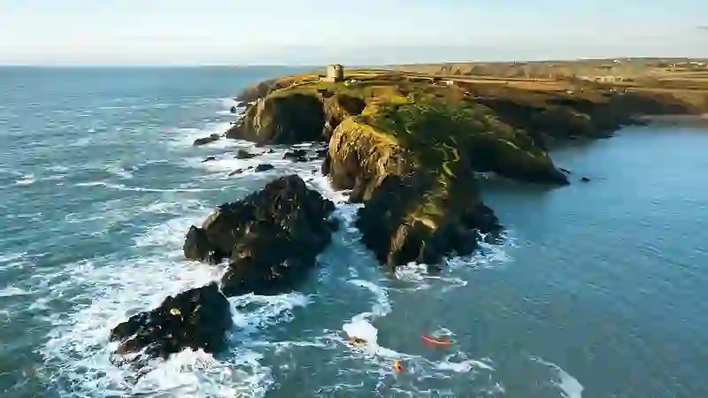 Baginbun Head cliffs with kayakers exploring the rugged coastline of County Wexford.