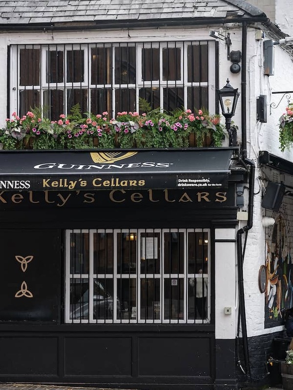 Kelly’s Cellars pub in Belfast, with Guinness signage, flower boxes and people outside on a busy street.