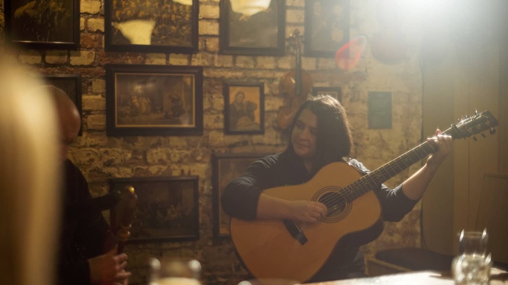 Musician on the Belfast Trad Trail playing guitar during a traditional music session in a cosy Belfast pub.
