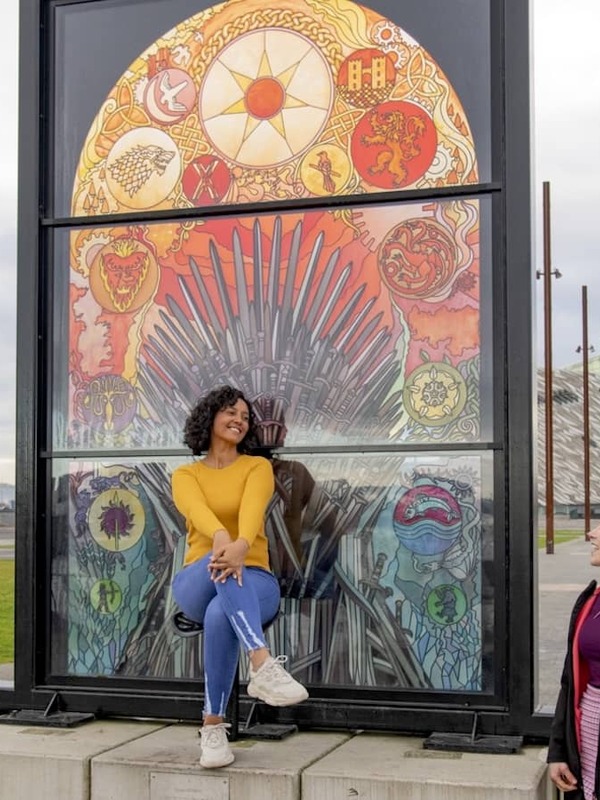 Friends posing beside the Glass of Thrones stained-glass artwork in Belfast’s Titanic Quarter.