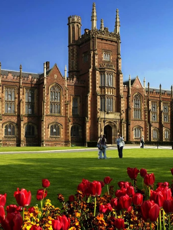 La Queen's University di Belfast, circondata da tulipani rossi in fiore sotto il sole di primavera.