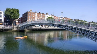 Kayaker paddling under the Ha’penny Bridge on the River Liffey in Dublin city centre.