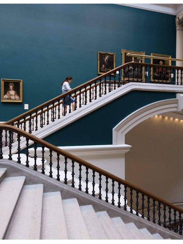 Besucher steigen unter klassischen Porträts die große Treppe in der National Gallery of Irland hinauf.