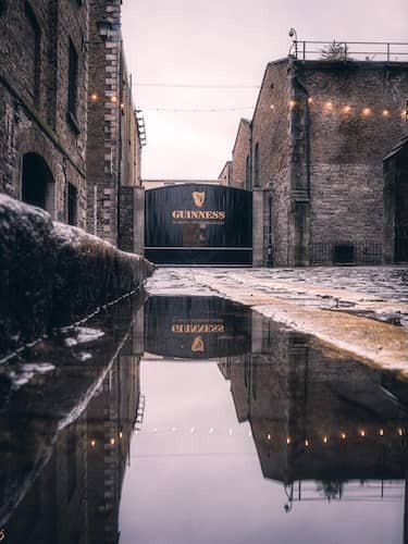 Historic Guinness gate at St James’s Gate Brewery, Dublin, with cobbled stones and soft string lights.