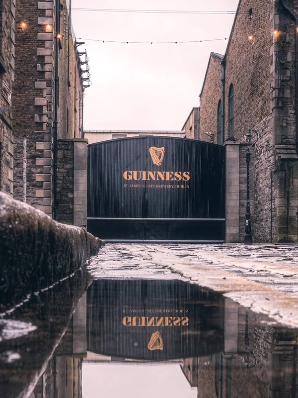 Historic Guinness gate at St James’s Gate Brewery, Dublin, with cobbled stones and soft string lights.