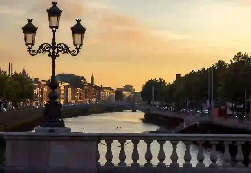 View of O'Connell Bridge and city skyline lit by golden evening light over the River Liffey.
