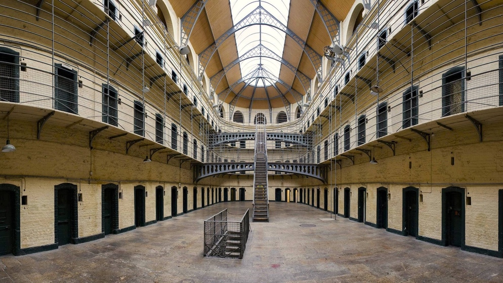 Interior of Kilmainham Gaol’s east wing with iron railings, arched ceiling, and historic prison cells.
