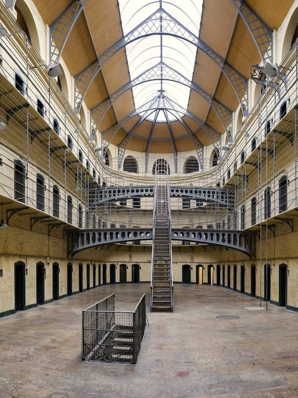 Interior of Kilmainham Gaol’s east wing with iron railings, arched ceiling, and historic prison cells.