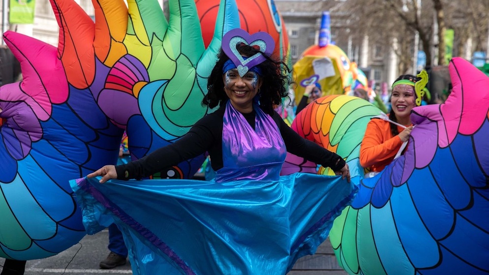 Performer in colourful costume smiling during Dublin's St Patrick's Day parade.