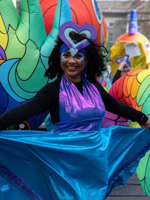 Performer in colourful costume smiling during Dublin's St Patrick's Day parade.