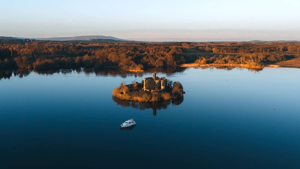 Castillo de McDermott en una pequeña isla en Lough Key, rodeado de aguas tranquilas durante la hora dorada, condado de Roscommon.