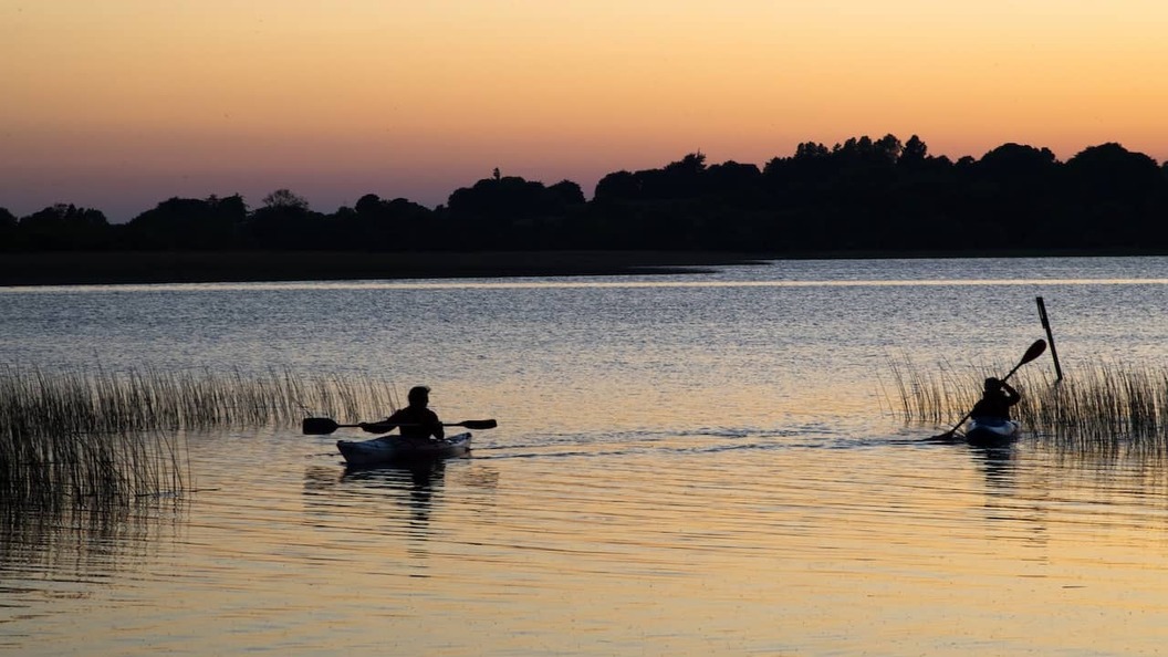 Kajakfahrer paddeln bei Sonnenuntergang auf einem ruhigen See in der Nähe von Glasson, Grafschaft Westmeath.