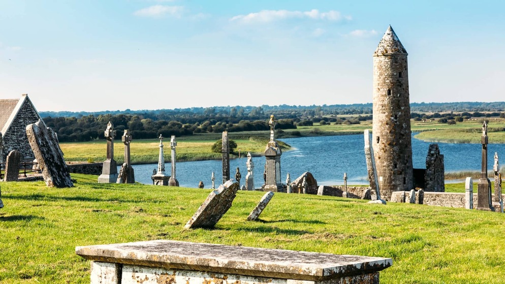 Ancient monastic site of Clonmacnoise, County Offaly, featuring a round tower and Celtic crosses overlooking the River Shannon.