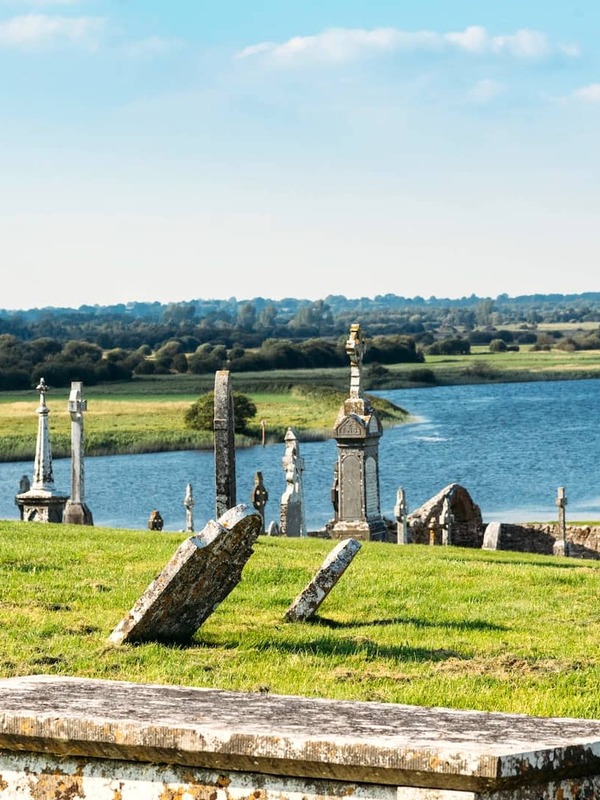 Ancient monastic site of Clonmacnoise, County Offaly, featuring a round tower and Celtic crosses overlooking the River Shannon.