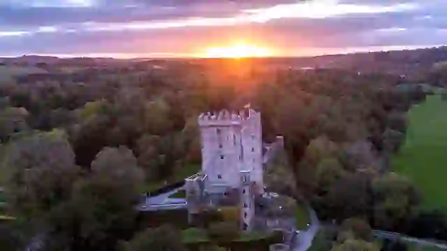 Blarney Castle surrounded by woodland at sunset in County Cork, Ireland.