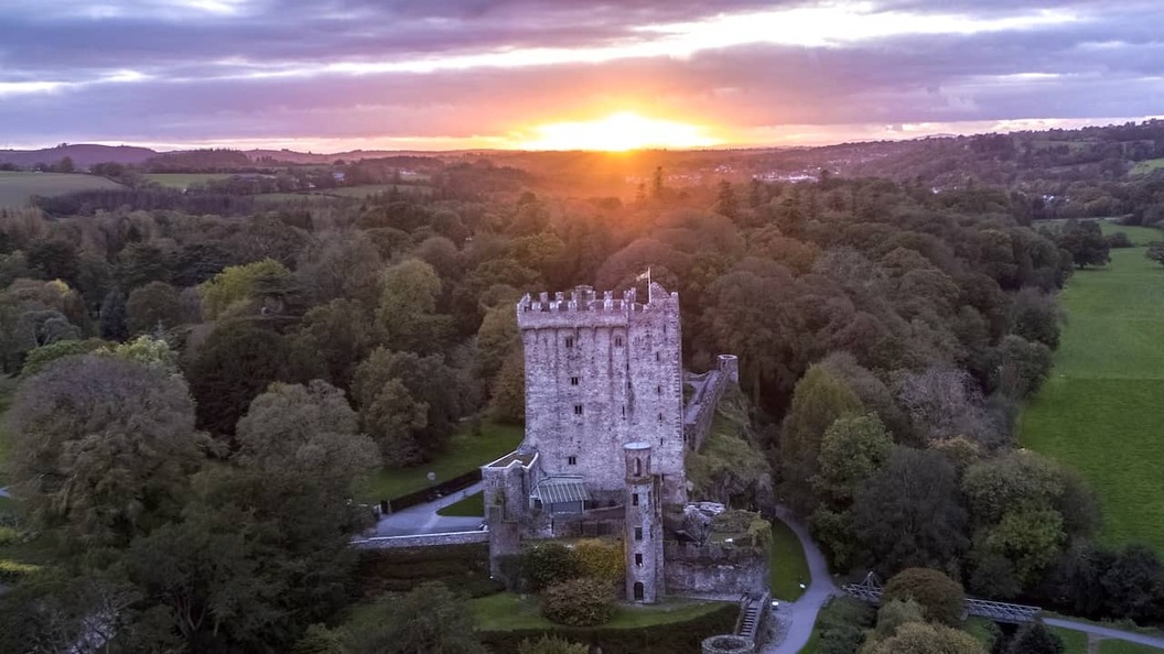 Blarney Castle surrounded by woodland at sunset in County Cork, Ireland.