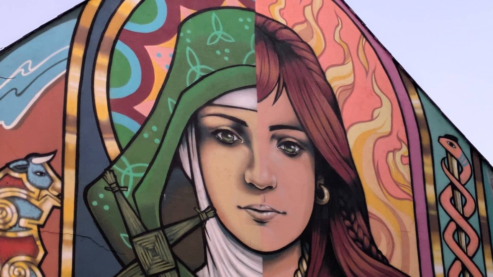 Colourful mural of a woman’s face inspired by St Brigid, painted with Celtic symbols and patterns.