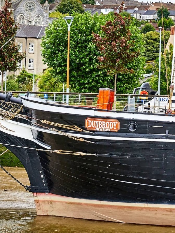 Dunbrody Famine Ship moored on the River Barrow in New Ross, County Wexford, with historic buildings behind.