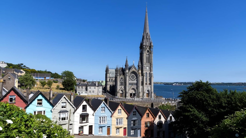 St Colman’s Cathedral towering above colourful houses in Cobh, overlooking Cork Harbour on a sunny day.