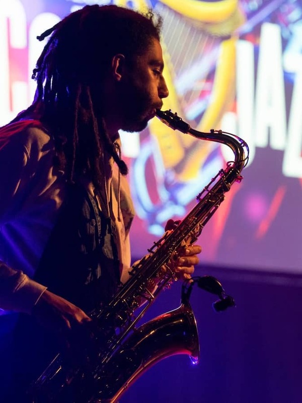 Saxophonist performing on stage under colourful lights at the Cork Jazz Festival.