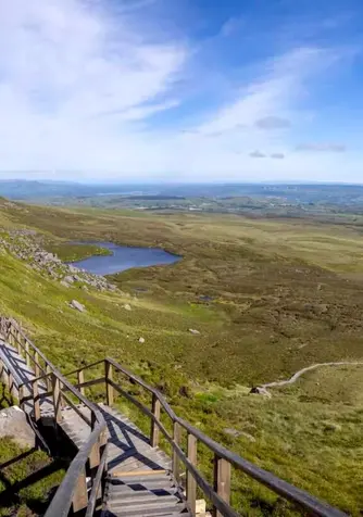 Wooden boardwalk trail winding through the Cuilcagh Mountain uplands with panoramic views across County Fermanagh.