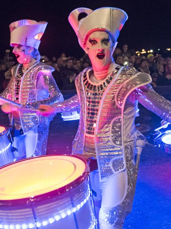 Straatmuzikanten in zilveren kostuums die het publiek vermaken tijdens de Halloween-nachtparade in Derry.