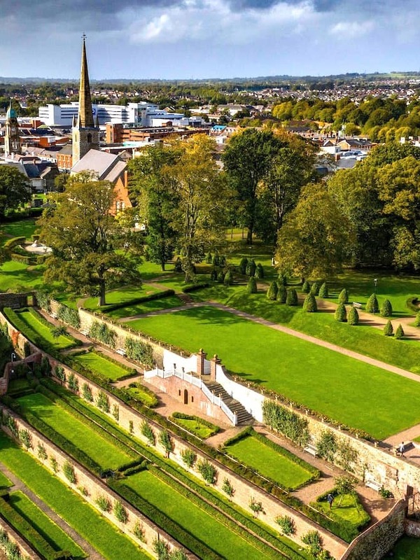 Terraced lawns and formal landscaping of Castle Gardens overlooking Lisburn city in County Antrim under autumn skies.