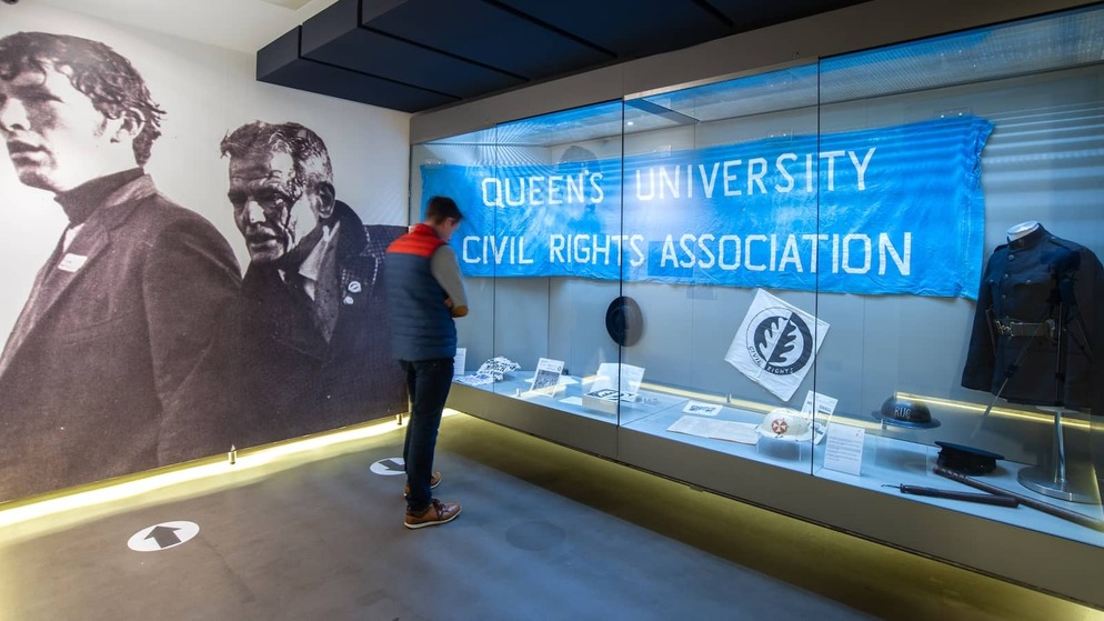Visitor observing civil rights exhibits at the Museum of Free Derry, with banners and protest memorabilia.