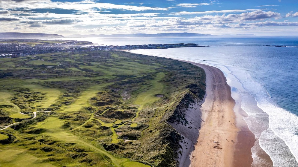 Rolling dunes and wide fairway with a green in the distance under a hazy sky near County Louth.
