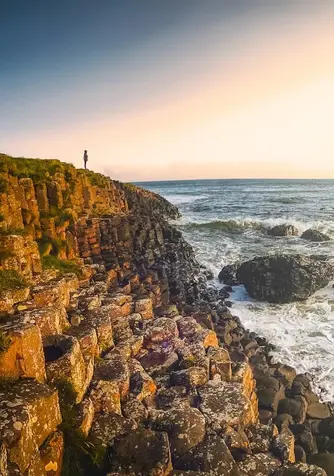 Sonnenuntergang über dem Giant's Causeway (Damm des Riesen) in der Grafschaft Antrim, mit gleichmäßig geformten Basaltsäulen entlang der zerklüfteten Küste.