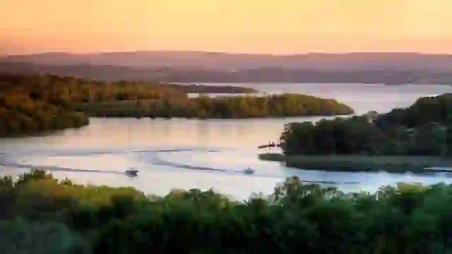 Aerial view of boats cruising across Lough Erne beside White Island and Archdale Forest Park in County Fermanagh at sunset.