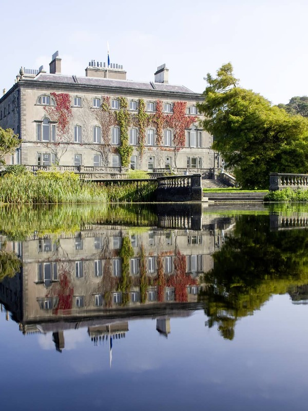 Das elegante Westport House in der Grafschaft Mayo spiegelt sich in einem stillen See, umgeben von üppigen Gärten und alten Bäumen.