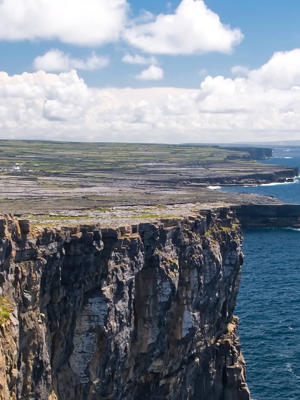 Besucher erkunden felsige Klippen neben der alten Steinfestung Dún Aonghasa auf den Aran Islands in Galway.