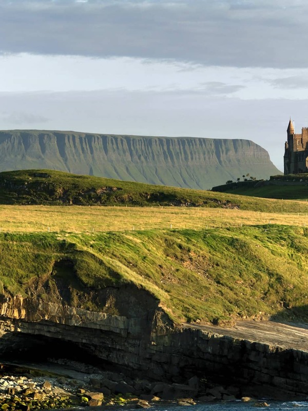 Classiebawn Castle perched on green headland with Ben Bulben mountain in the background, County Sligo.
