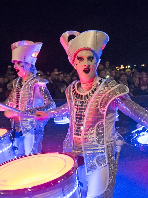 Street performers in silver costumes play drums during Halloween celebrations in Derry~Londonderry.