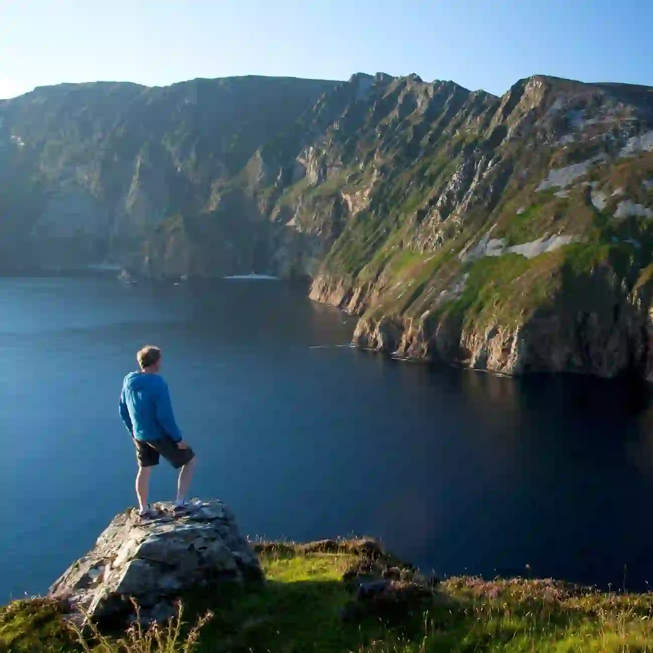 Man standing on viewpoint above the towering Slieve League sea cliffs in County Donegal, Ireland.