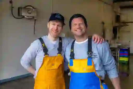 Dermot O'Leary and worker in yellow waterproofs smiling inside Molloy’s seafood facility in Killybegs harbour.