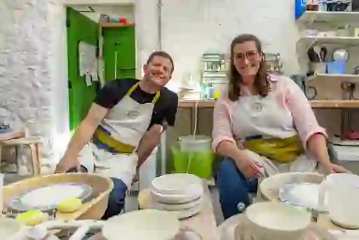 Dermot and potter at wheels in Blackheath Pottery studio in Coleraine, shaping clay bowls in a bright workshop.