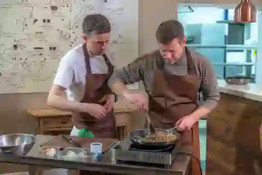 Dermot O'Leary and chef Chris Molloy cooking at The Lemon Tree restaurant, preparing food together in a modern kitchen setting.
