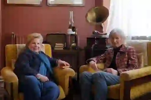 Sandi and the Director of The Yeats Society sit in yellow armchairs beside an antique gramophone, telephone and radio in a cosy room in County Sligo.