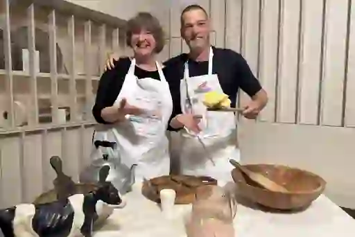 Fred and a tour guide in aprons presenting traditional butter-making tools and fresh butter inside the Butter Museum in Cork.