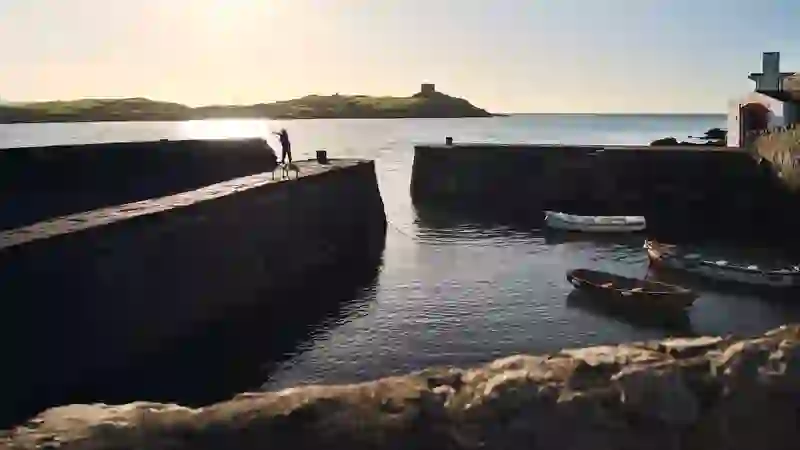 Boats moored at Colliemore Harbour in Dalkey, Dublin, with sunlit sea views and stone piers.