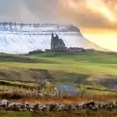 Classiebawn Castle on open fields beneath the dramatic cliffs of Ben Bulben at sunset.