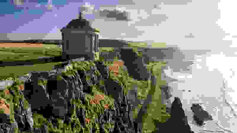 Der Mussenden Temple thront auf einer Klippe über einem endlosen Strand, während die Bahnlinie die Küste der Grafschaft Londonderry säumt.