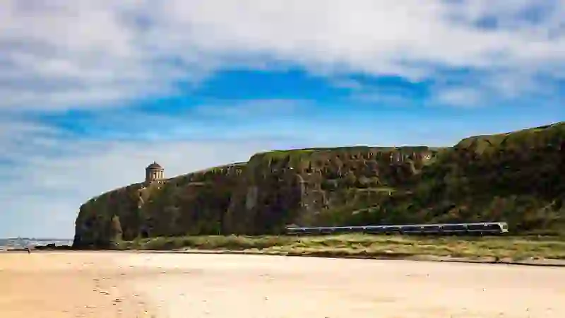 Train travels along Downhill Strand beneath Mussenden Temple on the Causeway Coast, County Londonderry.