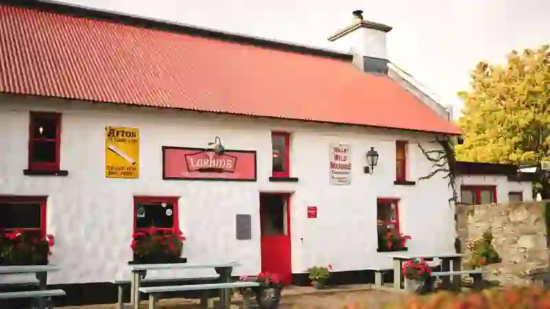 Larkin’s traditional whitewashed pub in County Tipperary with red roof, flower boxes and outdoor benches.